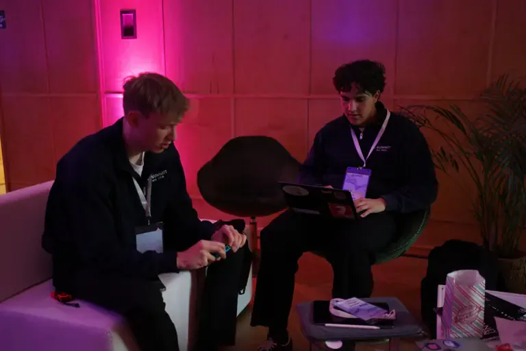 Two participants working on a laptop and a phone in a lounge corner